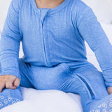 Child wearing a blue outfit with zippers on a white background