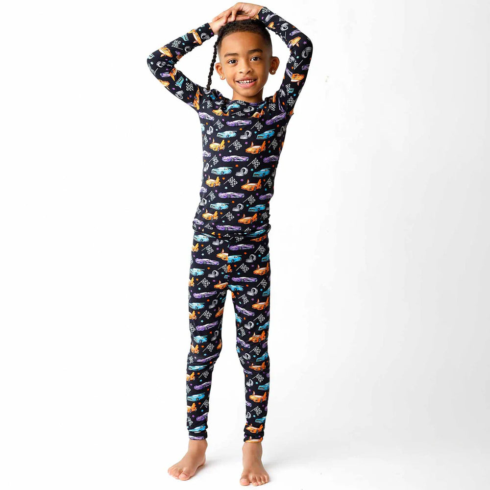 Child wearing a colorful pajama set with car pattern on a white background