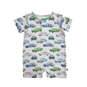 A close-up of a short-sleeve baby romper or bodysuit with an all-over vintage car print on a light cream background. The print features retro cars in light blue, medium blue, green, and white, with a buttoned chest pocket.