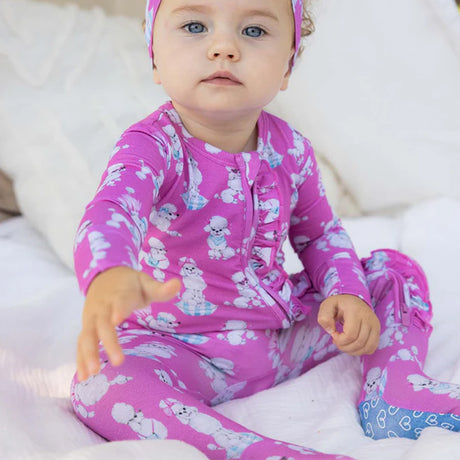 Baby in pink pajamas with animal pattern on a white blanket