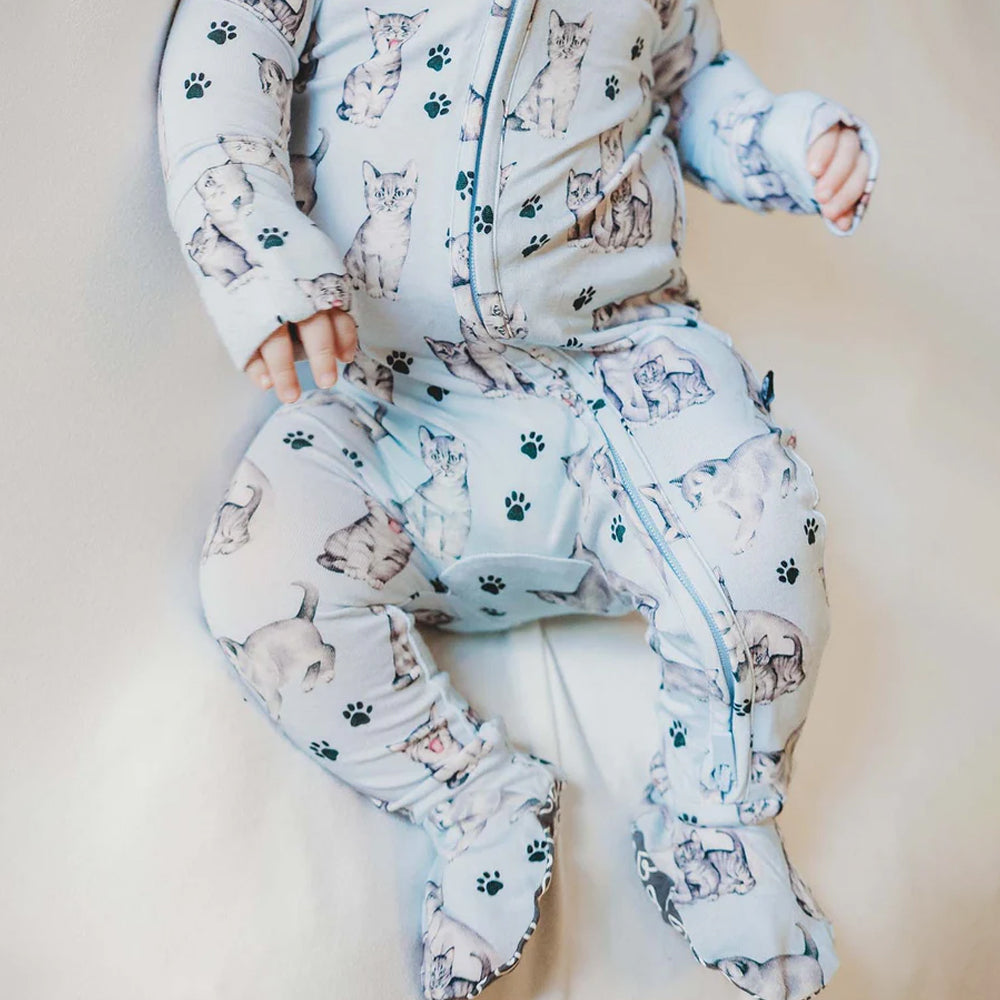 Baby in a onesie with cat print on a light background
