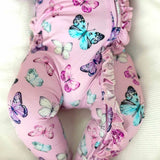 Pink baby leggings with a colorful butterfly print and ruffled trim, shown on a baby lying on a textured white blanket.