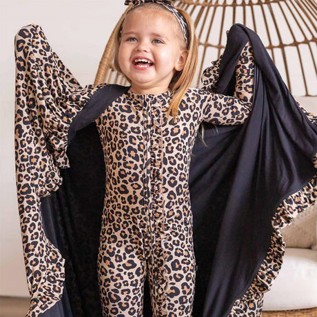 Child wearing a leopard print outfit with a black and leopard print blanket.