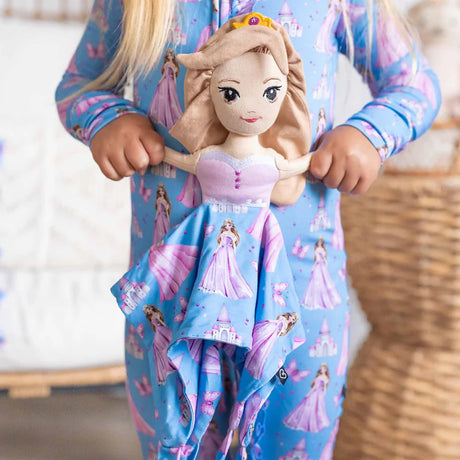 Child wearing blue pajamas with princess designs, holding a doll.