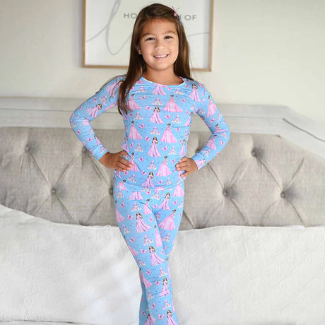 Child wearing a blue pajama set with pink princesses in a bedroom setting