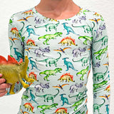 Person wearing a long-sleeve shirt with dinosaur pattern holding a toy dinosaur.