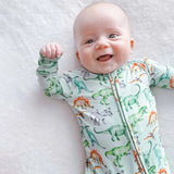 Baby wearing a dinosaur-patterned onesie on a white blanket