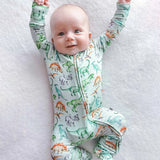 Baby wearing a dinosaur-patterned onesie on a white blanket