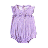 A lavender baby romper with a small floral print, featuring ruffle trim at the neckline and sleeve hems, laid flat on a white background.