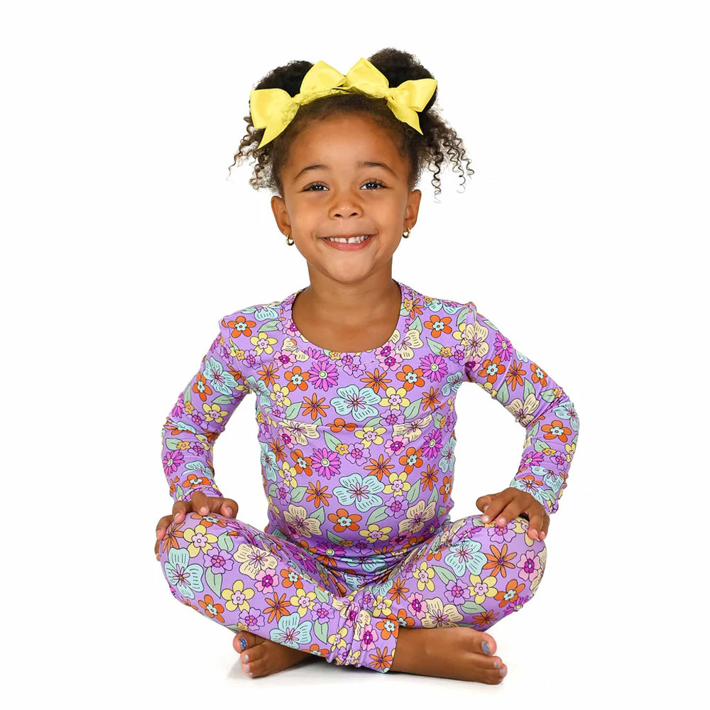 Child wearing a purple floral outfit on a white background