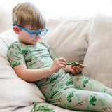 Child wearing green pajamas with vehicle pattern, sitting on a beige couch.