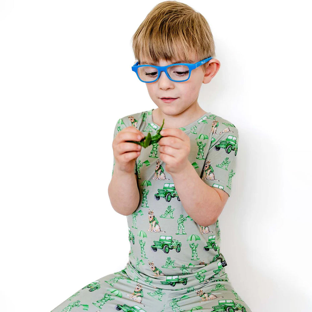 Child wearing a pajama set with green vehicle pattern on a white background