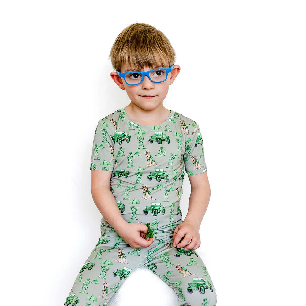 Child wearing a green pajama set with vehicle pattern on a white background