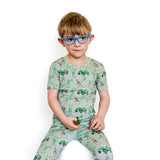 Child wearing a green pajama set with vehicle pattern on a white background