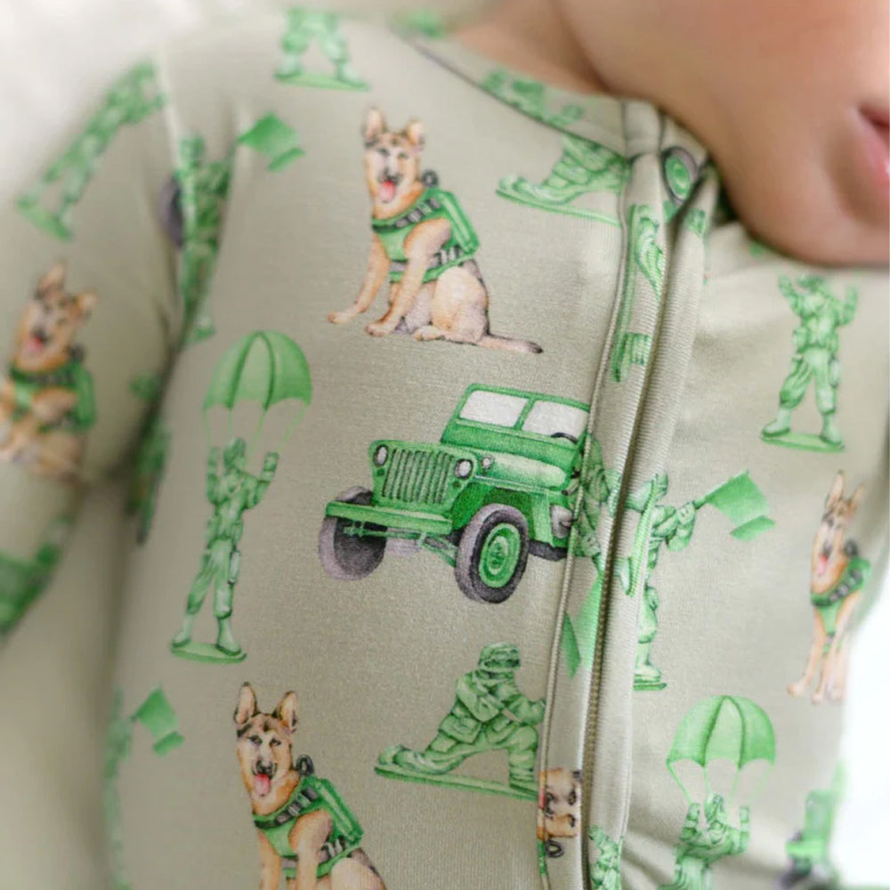Children's onesie with green and beige pattern featuring soldiers and a jeep.