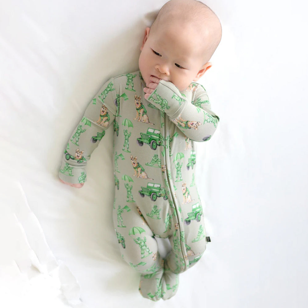 Baby wearing a green and gray patterned onesie on a white background