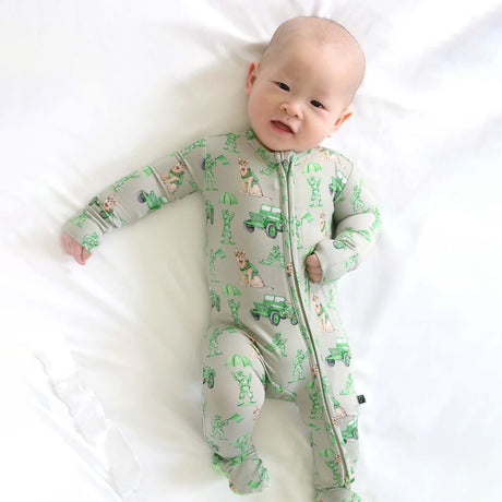Baby wearing a green and gray onesie with vehicle patterns on a white background