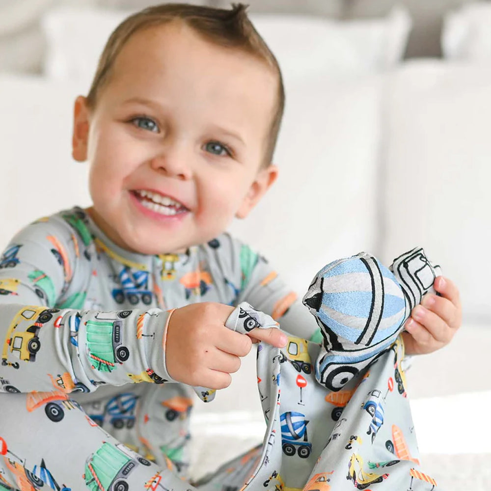 Child wearing a patterned outfit holding a colorful baby blanket.