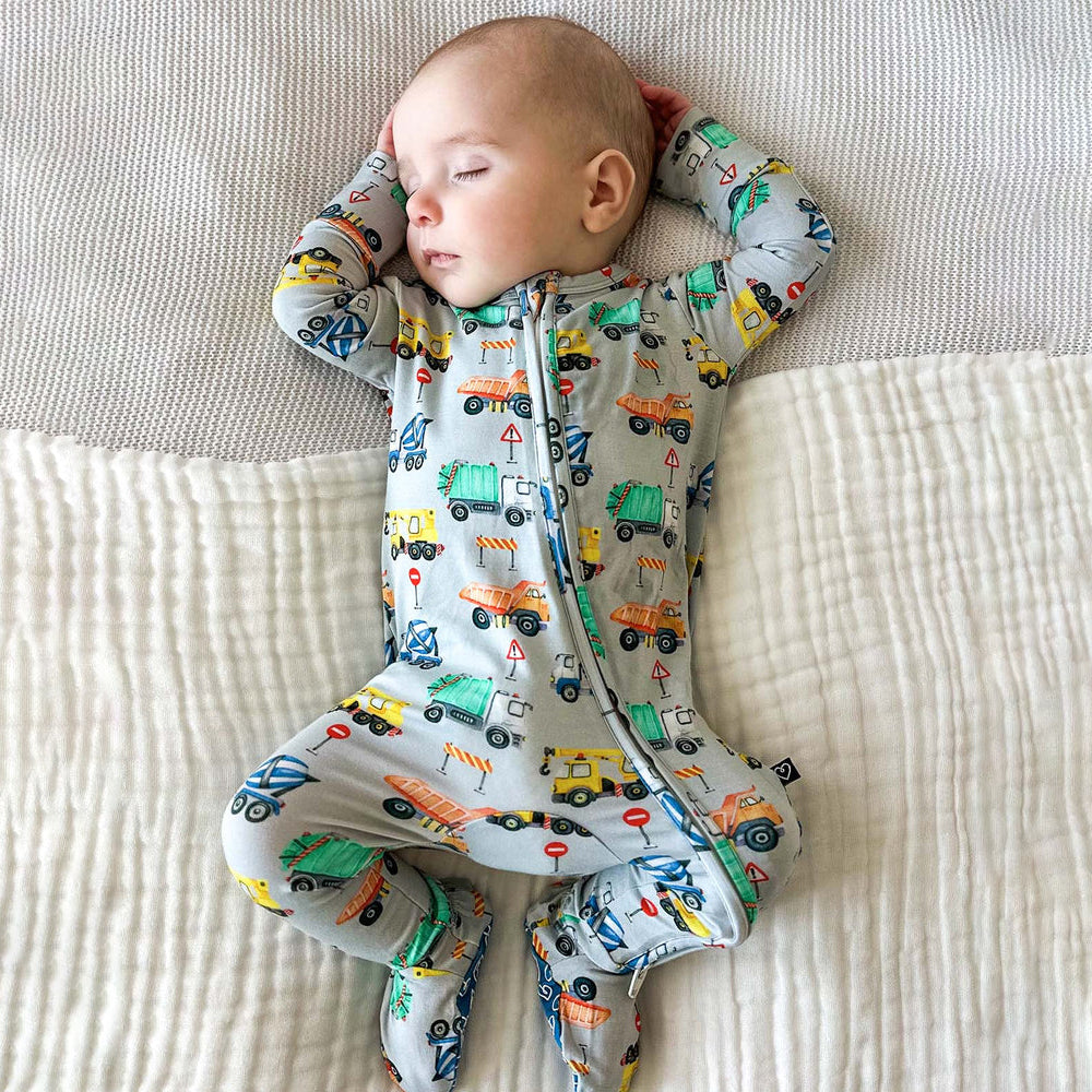 Baby wearing a onesie with vehicle pattern on a textured surface