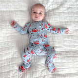 Baby wearing a gray onesie with red fox patterns on a striped bed.