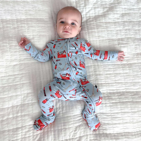 Baby wearing a gray onesie with red fox patterns on a striped bed.