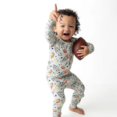 Baby wearing onesie with sports-themed print on a white background