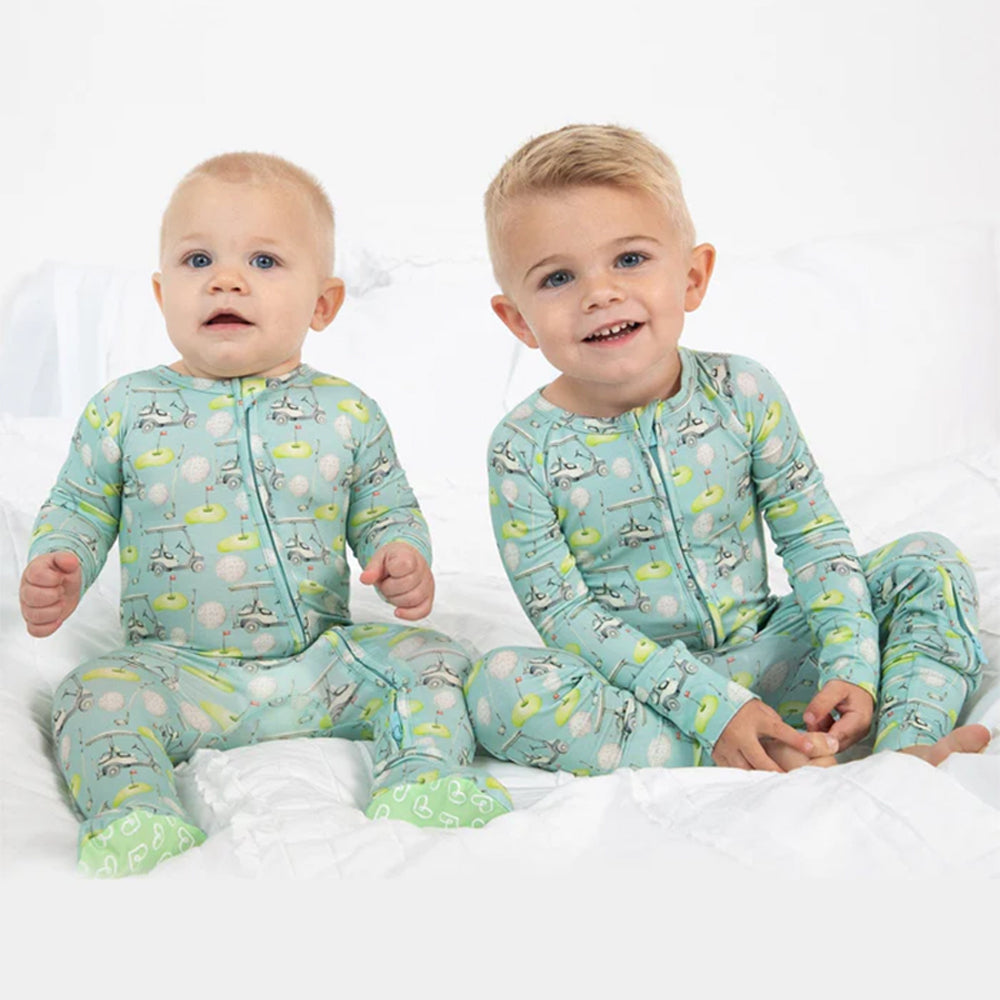 Two children wearing matching pajamas with a pattern of animals on a white background