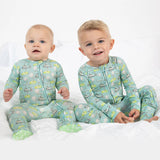 Two children wearing matching pajamas with a pattern of animals on a white background