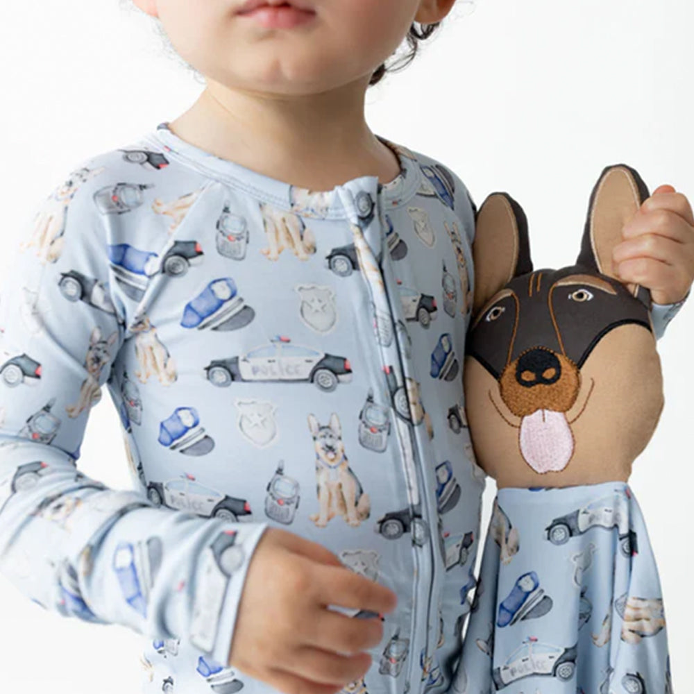 Child wearing a patterned onesie holding a plush dog toy.