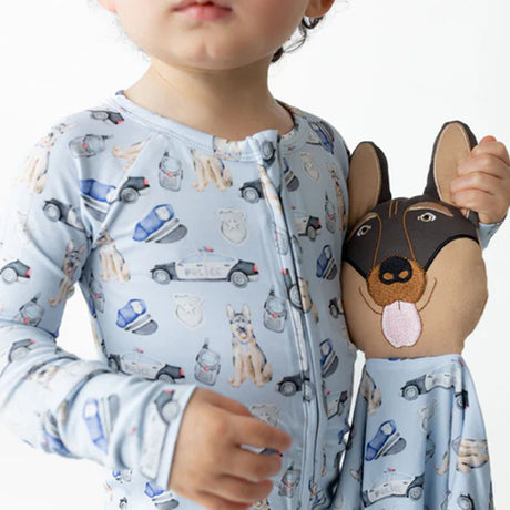 Child wearing a patterned onesie holding a plush dog toy.