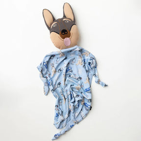Dog-shaped plush toy with a blue patterned blanket draped over it on a white background