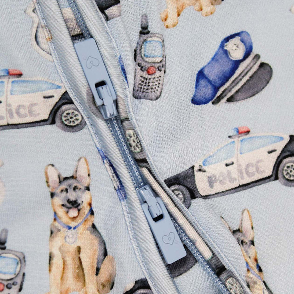 Close-up of a zipper on fabric with police-themed illustrations including dogs, cars, and radios.