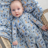 Baby in a crib with blue pajamas featuring animal and car patterns.