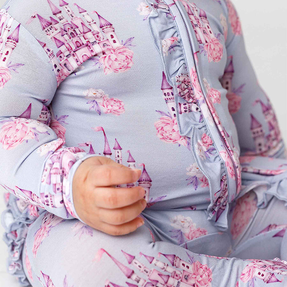 Child wearing a light blue outfit with pink castle pattern