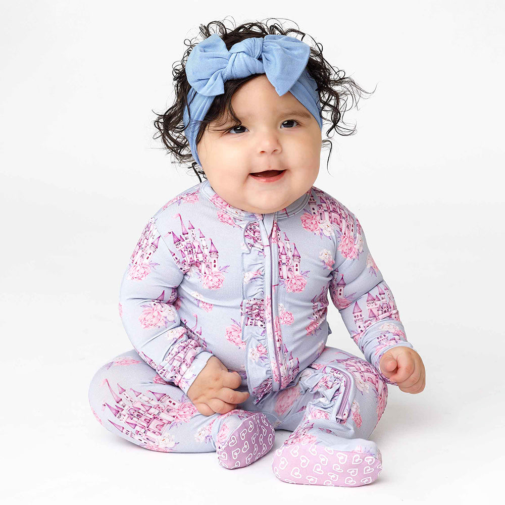 Baby wearing a floral onesie and headband on a white background