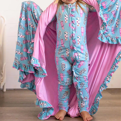 Child wearing a blue pajama set with pink ruffled accents, standing against a white background.