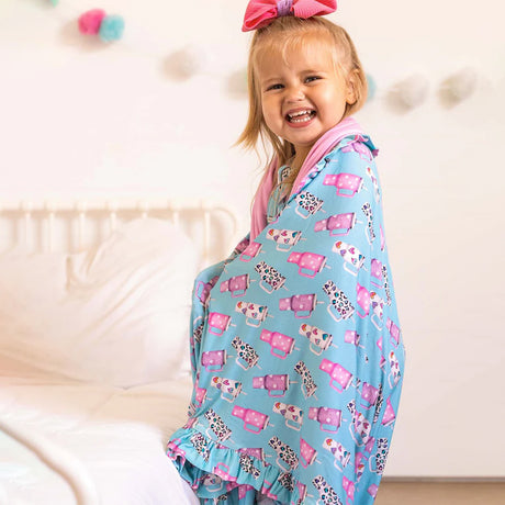 Child wearing a blue blanket with pink and white patterns on a white background