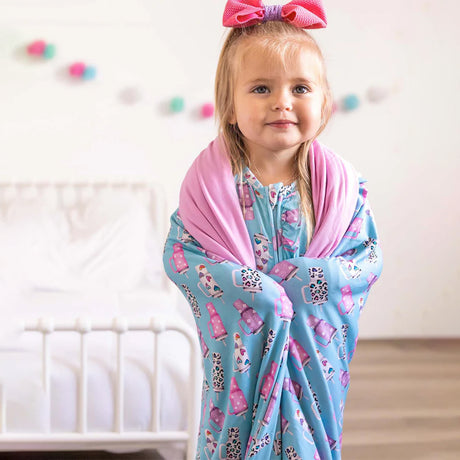 Child wearing a blue blanket with pink and white patterns on a white background