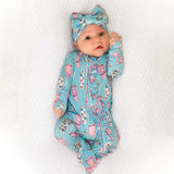 Baby in a blue and pink patterned outfit with a matching headband on a textured white background