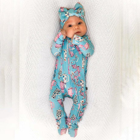 Baby in a blue floral outfit and headband on a textured white blanket