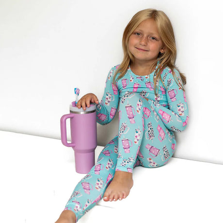 Child wearing a blue and pink pajama set with a purple tumbler.