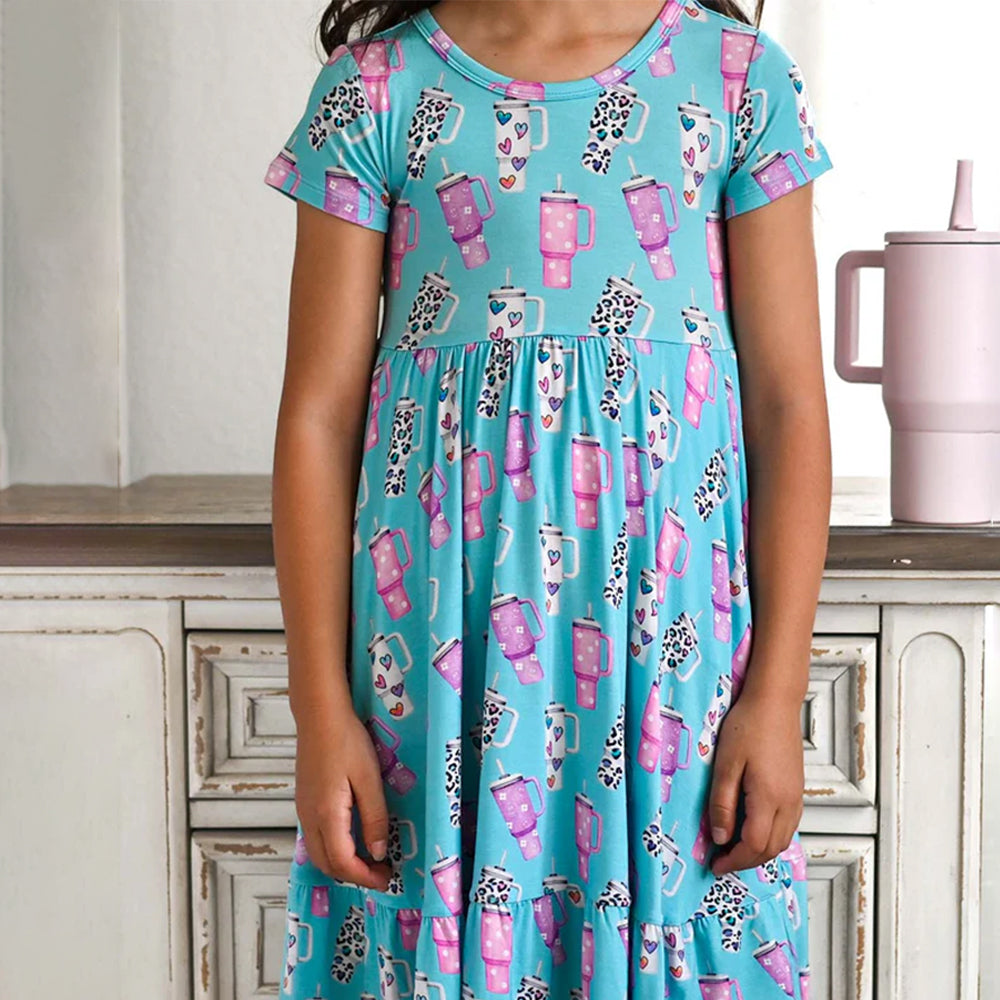 Child wearing a blue dress with pink mugs and leopard print pattern in a kitchen setting.