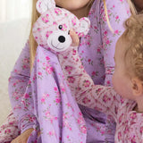 Child and adult in matching floral pajamas with a teddy bear plush toy.