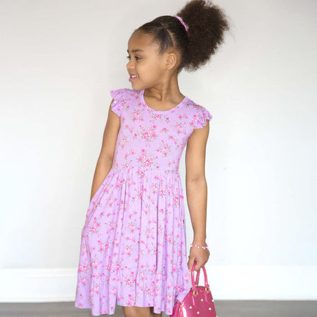 Young girl wearing a pink floral dress against a white background