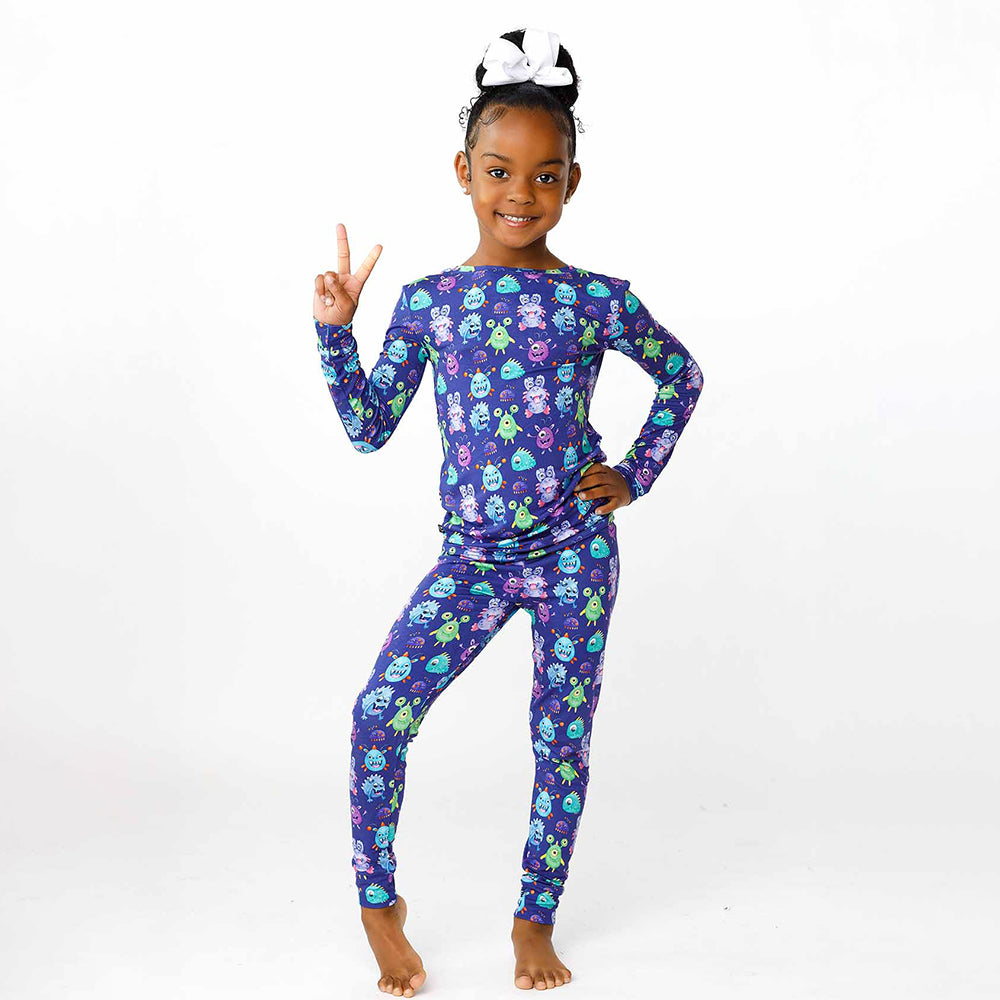 Child wearing a purple pajama set with a cartoon monster pattern on a white background