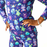 Person wearing a blue outfit with colorful monster pattern on a white background