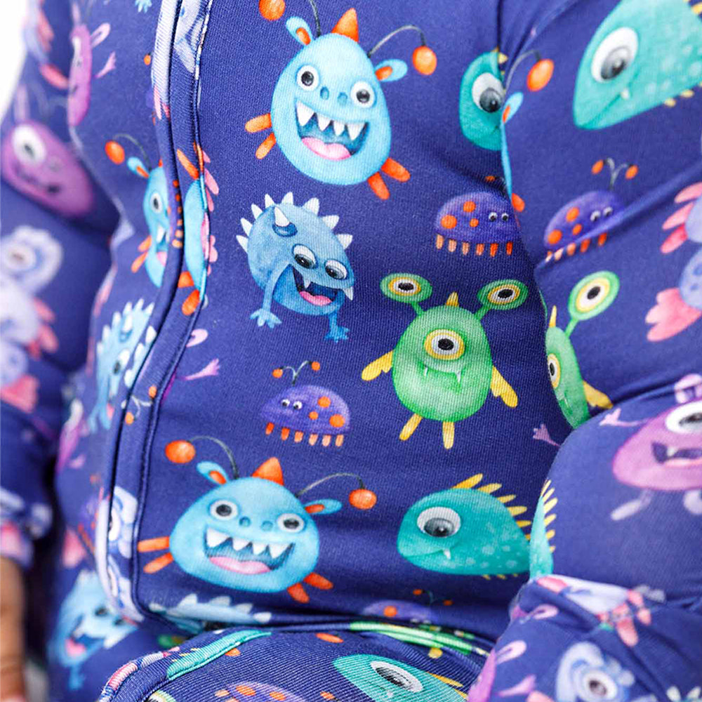 Children's onesie with colorful monster pattern on a blue background