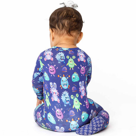Baby wearing a colorful monster-patterned onesie on a white background