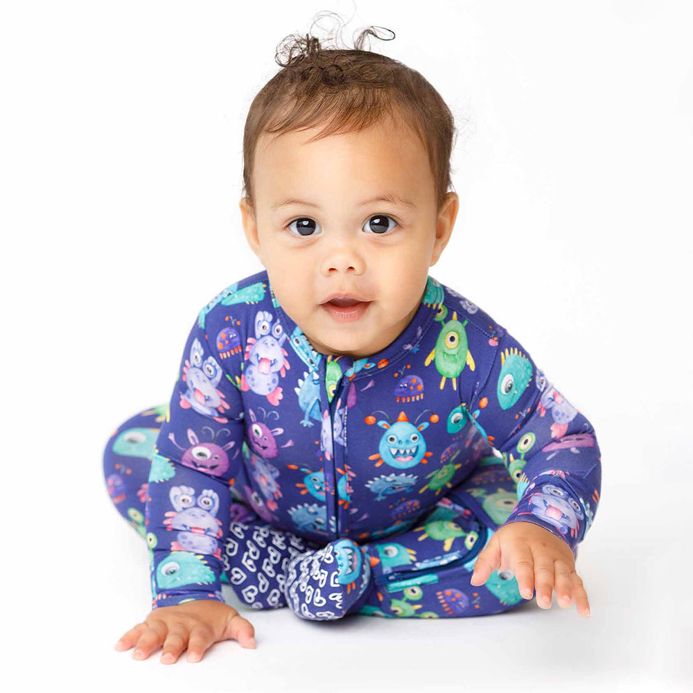 Baby wearing a colorful purple onesie with cartoon characters on a white background