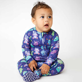 Baby wearing a colorful onesie with monster pattern on a white background
